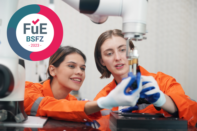 Zwei Personen an einem Industrieroboter, BSFZ-Siegel